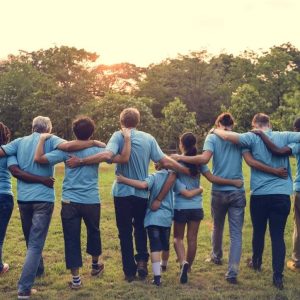 Volunteers wearing light blue shirts with their backs to the camera, walking into a sunset.